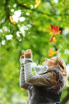 woman drop up leaves in autumn park