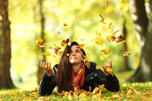 woman drop up leaves in autumn park