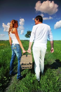 man and woman walk on picnic in green grass