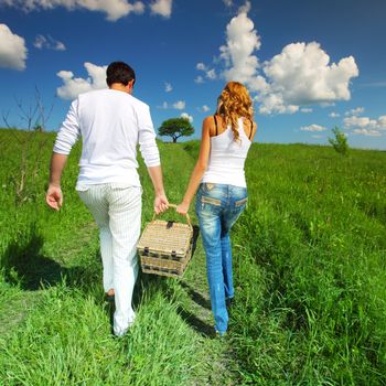 man and woman walk on picnic in green grass