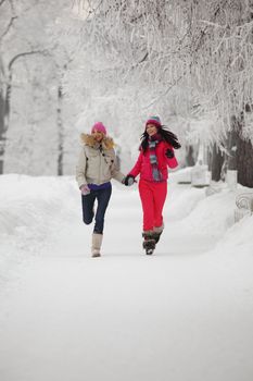 two winter women run by snow frosted alley