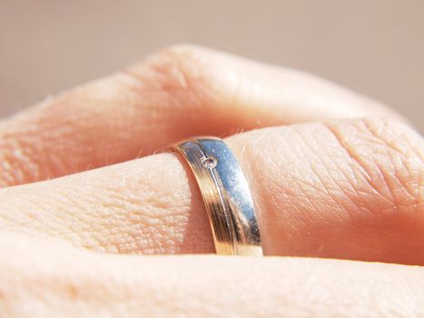 White and yellow gold ring, with a diamond, on male finger