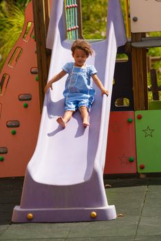 Joy sliding down a chute for a small Hispanic girl