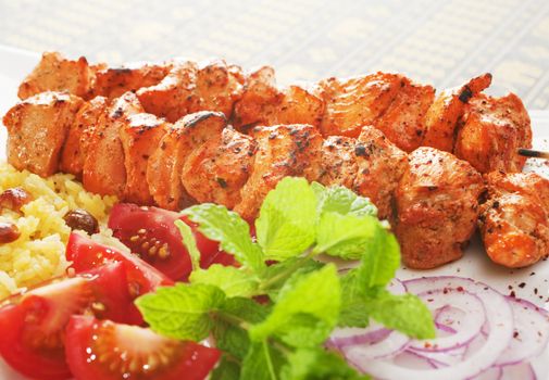 Indian meal of chicken tikka with rice and salad. Focus is on chicken.