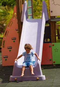 Small Hispanic girl sliding down a chute