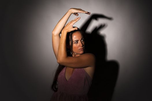 Dancer in a strong, expressive attitude with shadow on wall