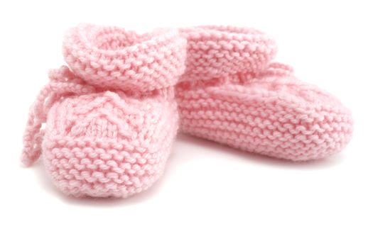 Pair of hand knitted pink baby booties on white background