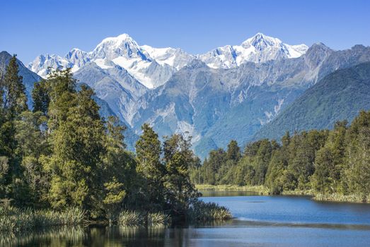 Lake Matheson with snow covered Mount Tasman and Mount Cook, New Zealand's highest mountain. Mount Cook is on the right.