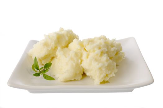 A plate of mashed potato and a sprig of basil, isolated on white