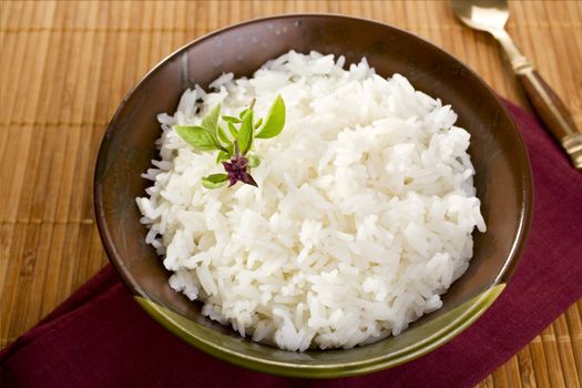 Thai fragrant jasmine rice in a bowl, with a garnish of Thai basil which is in flower.