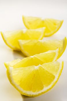 Five lemon wedges on a white plate. This is not an isolation.