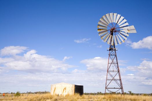 Windmill in Queensland, Australia, with blue sky and fluffy white clouds
