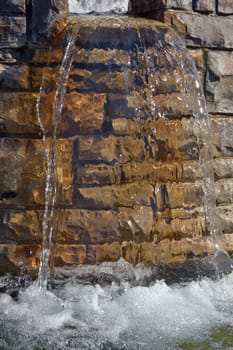 Fountain waterfall in sunlit on stone background