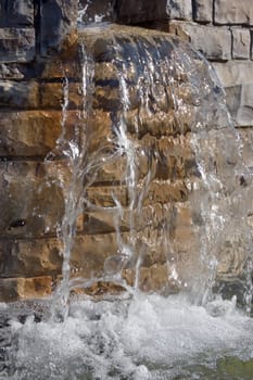Fountain waterfall in sunlit on stone background