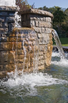Fountain waterfall in sunlit on stone background