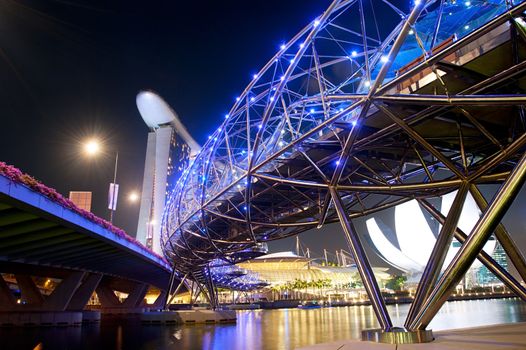 Singapore, Republic of Singapore - March 06, 2013:  The Helix Bridge and Marina Bay Sands at night.  The Helix is fabricated from 650 tonnes of Duplex Stainless Steel and 1000 tonnes of carbon steel.