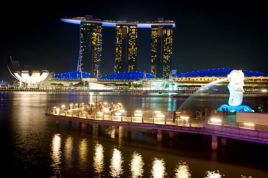 Singapore, Republic of Singapore - March 08, 2013: The Merlion fountain spouts water in front of the Marina Bay Sands hotel. Merlion is an imaginary creature with the head of a lion, often seen as a symbol of Singapore