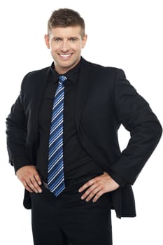 Confident young businessman posing casually. Hands on his waist
