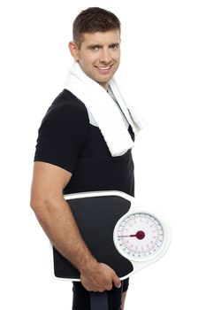 Healthy young man with a weight scale. Isolated over white background