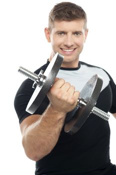 Cheerful young gym instructor posing with heavy dumbbell over white background