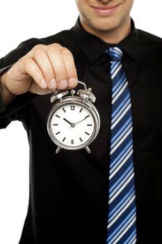 Business executive holding alarm clock over white background. Cropped image