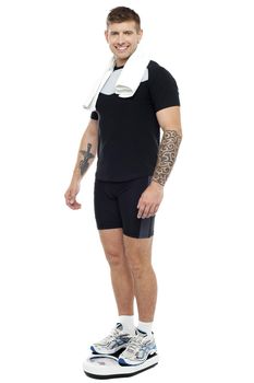 Fit man checking his weight after the workout isolated against white background