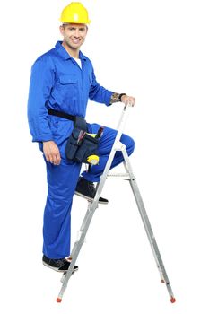 Cheerful young construction worker climbing up the stepladder