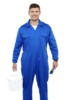 Portrait of a friendly painter holding bucket and paint brush isolated on white