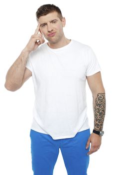 Casual young smart guy thinking hard while looking at camera