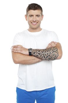 Picture of a young smiling masculine chap with huge tattoos drawn on his hand. Arms folded