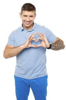 Smiling young man making heart with his fingers