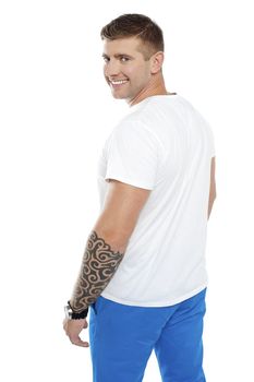 Young smiling man with tattoo on hand turning back towards camera