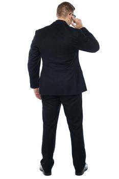 Back pose of young male security person holding earpiece and listening carefully