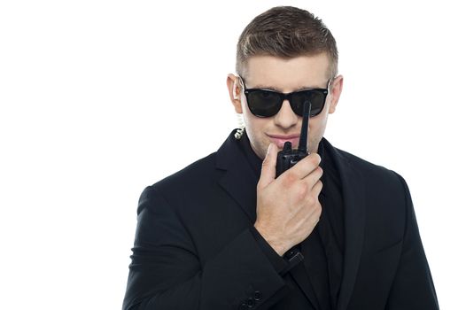 Smart young security personnel communicating over the walkie-talkie isolated over white background