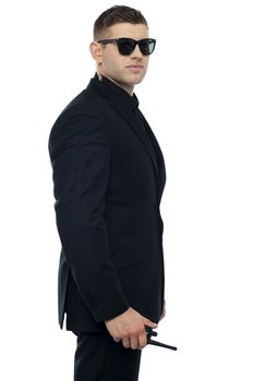 Side pose portrait of young and smart security officer holding walkie-talkie device in hand