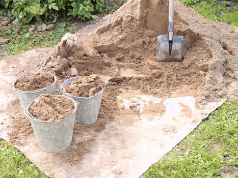 pile of sand, a shovel and a buckets of sand