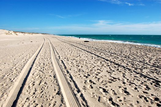 Car track on white sand beach, Australia