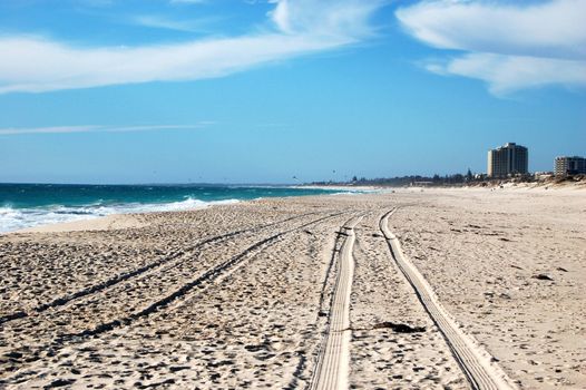 Car track on white sand beach