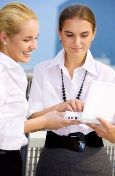 two happy businesswomen with laptop computer in the city (focus on brunette)