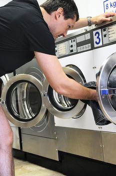 man is using washing machines in a public laundromat 