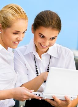 two happy businesswomen with laptop computer (focus on blonde)