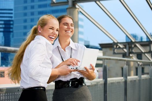 two happy businesswomen with laptop computer in the city