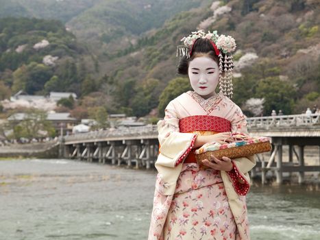 Maiko at togetsukyo bridge in kyoto, japan