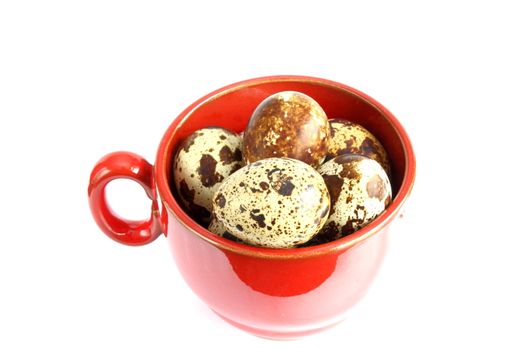 small quail eggs in red mug over white