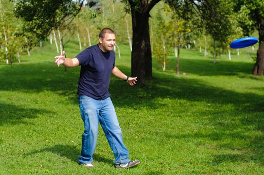 Young man playing frisbee on green grass