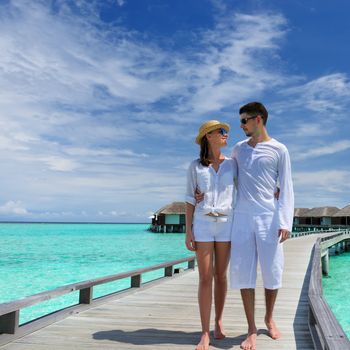 Couple on a tropical beach jetty at Maldives