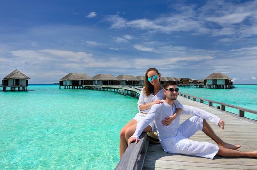 Couple on a tropical beach jetty at Maldives