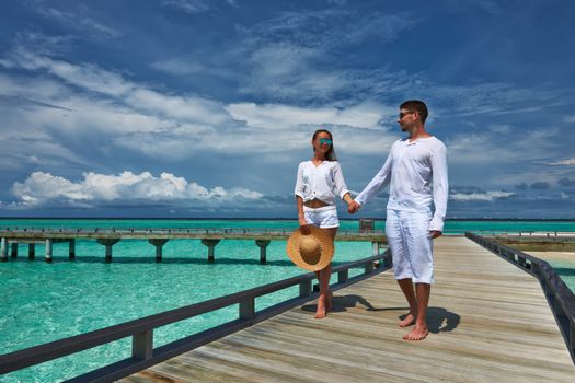 Couple on a tropical beach jetty at Maldives