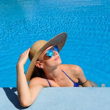 Woman in hat relaxing at the pool 