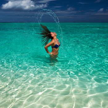 Woman splashing water with her hair in the ocean